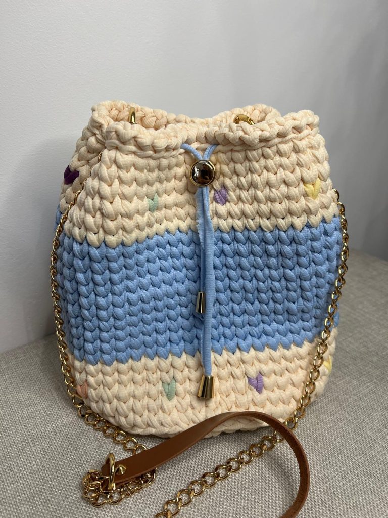 sac seau crochet bleu ciel et crème avec détails pastel et chaîne dorée, création artisanale de Vanda à Albi