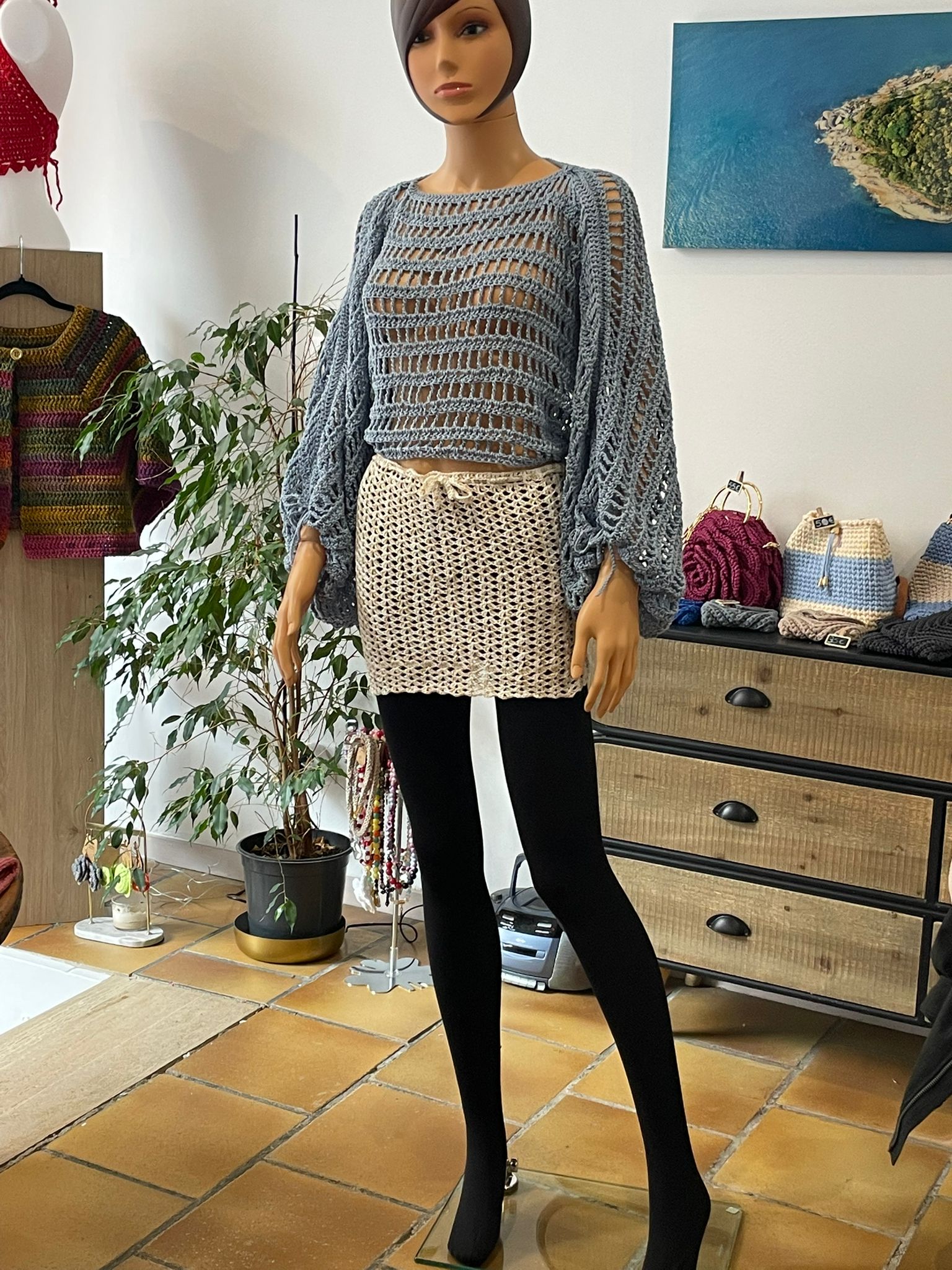 Top court pour femme en crochet couleur bleu acier gris. Modèle à manches longues bouffantes (style manches ballon) et maille ajourée transparente. Vêtement bohème chic fait main par Vanda Albi.
