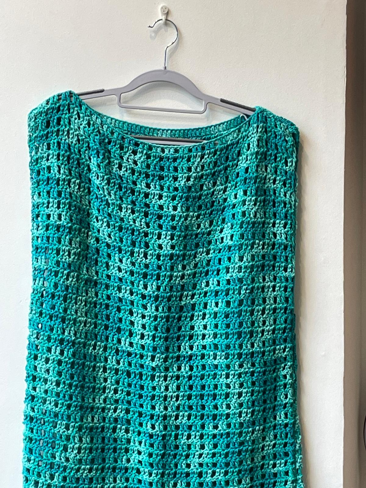 Tunique sans manches pour femme en crochet, couleur bleu turquoise et lagon nuancé. Point de maille aéré type filet, col bateau. Vêtement d'été artisanal présenté sur cintre et sur mannequin. Création Vanda Albi.