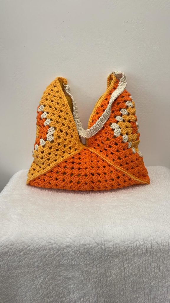 Sac hobo au crochet 100% coton orange mandarine et jaune safran, construit sur granny square géant, fait main par Vanda dans son atelier d'Albi – forme souple et graphique, anses écru avec anneau doré, pièce unique personnalisable
