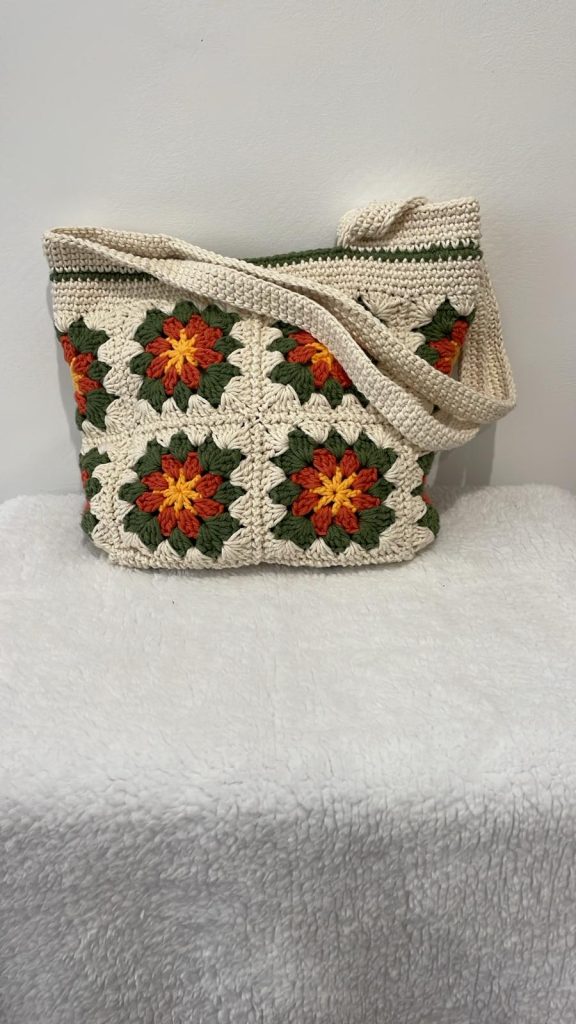 Tote bag au crochet 100% coton écru composé de granny squares fleuris terracotta, orange, jaune et vert kaki, fait main par Vanda dans son atelier d'Albi – pièce unique, doublure intérieure, fermeture bouton pression, personnalisable sur commande